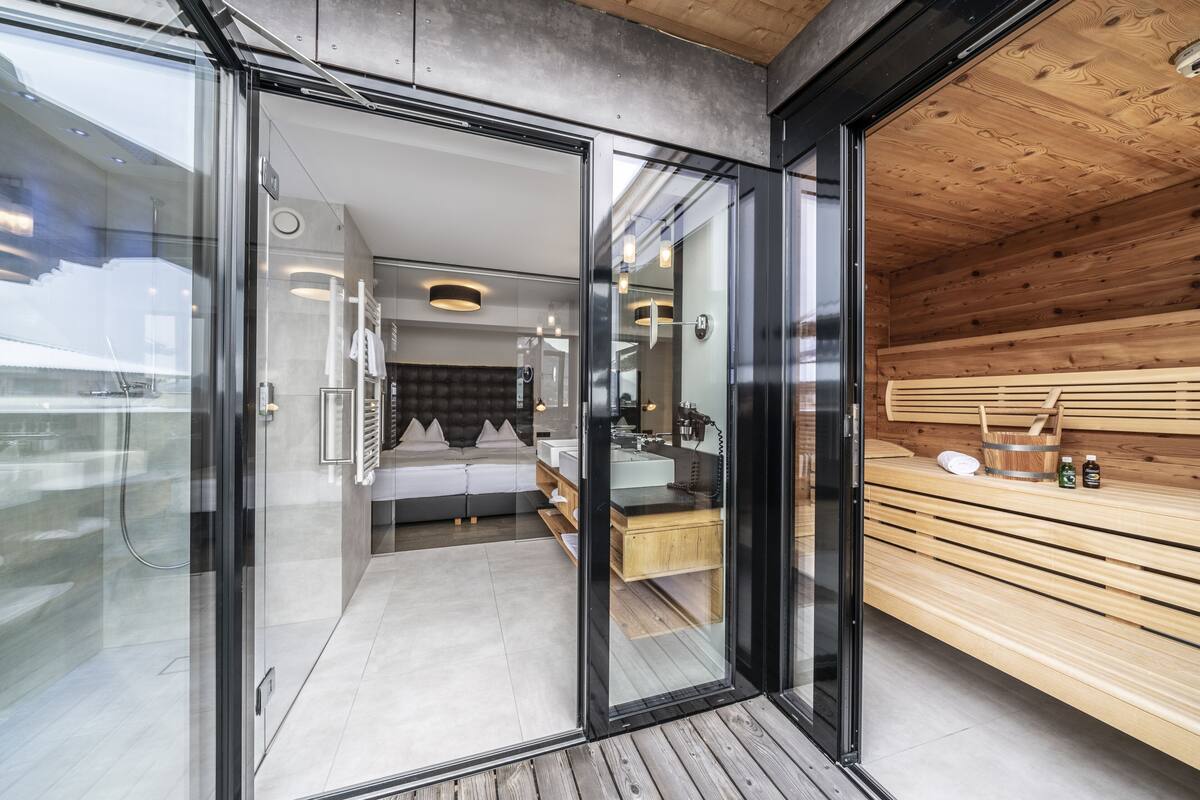 Une salle de bain moderne avec une douche à parois de verre, un banc en bois et un espace lavabo bien visible.