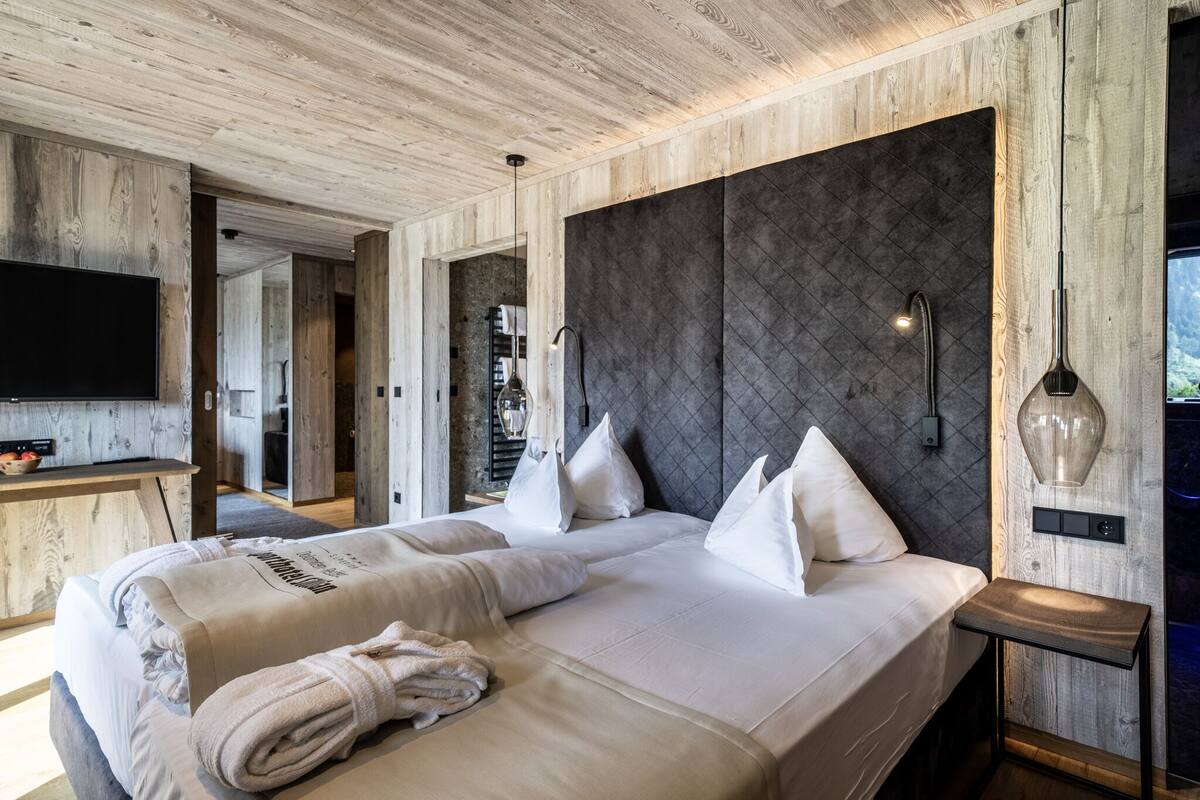 Une chambre d’hôtel moderne dotée d’un grand lit, d’un téléviseur à écran plat et d’un plafond en bois.