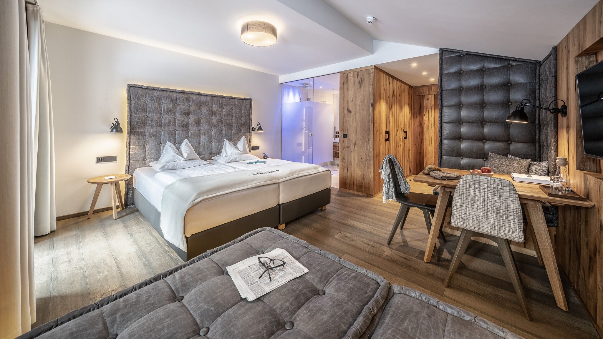 A modern hotel room with a large bed, a desk, and a comfortable seating area.
