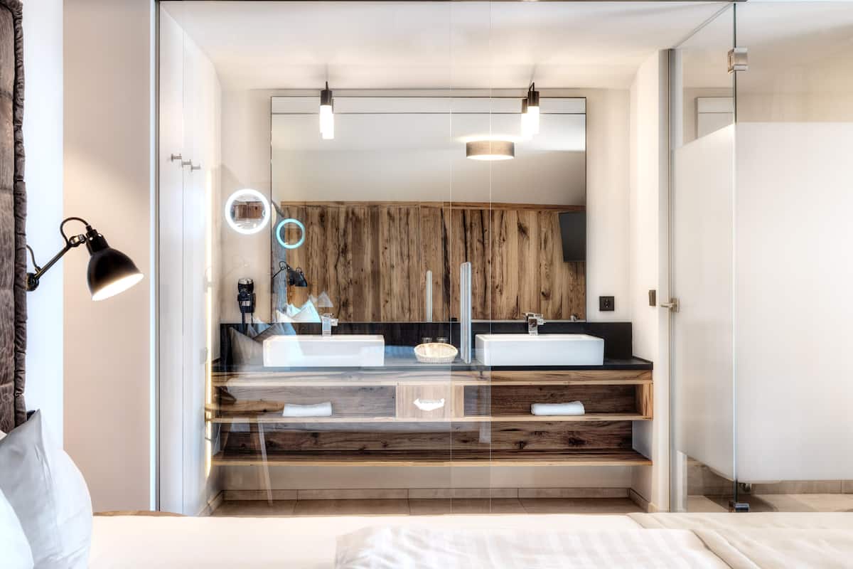 Une salle de bain moderne avec un grand miroir, deux vasques et un meuble-lavabo en bois.