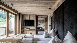 Quarto de hotel moderno com uma cama grande, televisão e vista para o exterior.