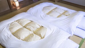 Two beds with unique pillow designs, a tatami mat floor, and a small table with a lamp. - Ariston Hotel Kobe (Kobe)