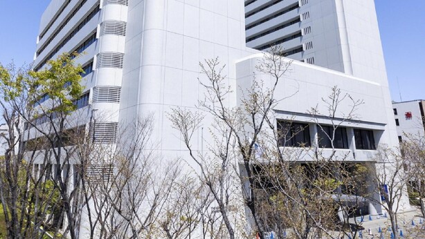 A modern building with a prominent logo on the facade, multiple floors, and a clear sky in the background. - Ariston Hotel Kobe (Kobe)