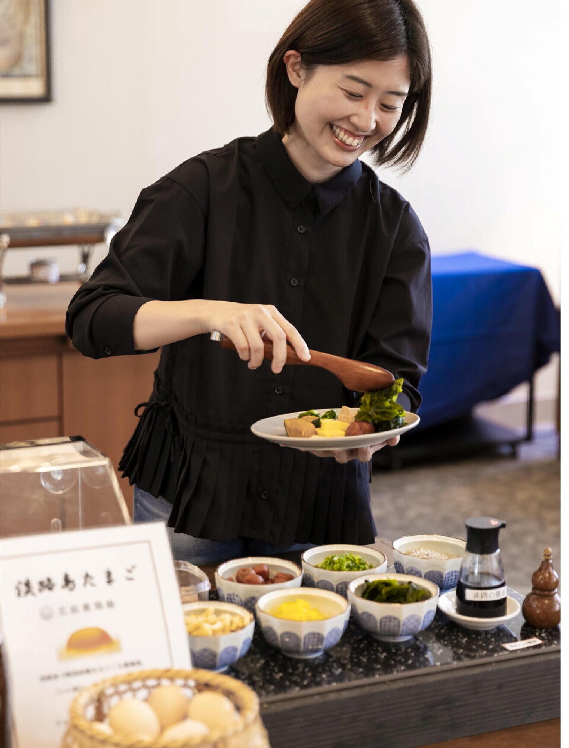A person serving food at a buffet with various dishes and condiments on display.