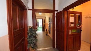 Corredor com portas de madeira, um vaso de planta e um aviso indicando que o quarto está disponível.