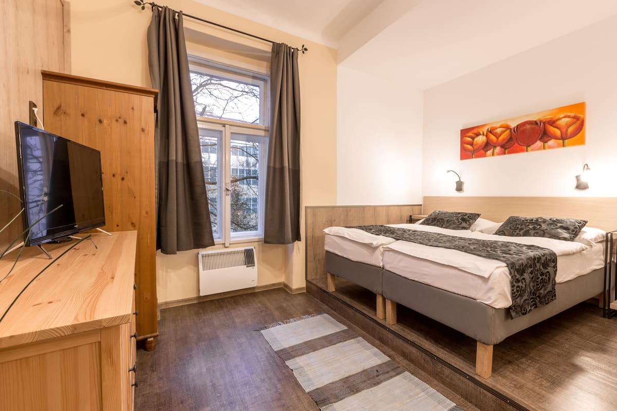 Ein Schlafzimmer mit einem Bett, einem Fernseher und einem Fenster mit Vorhängen.