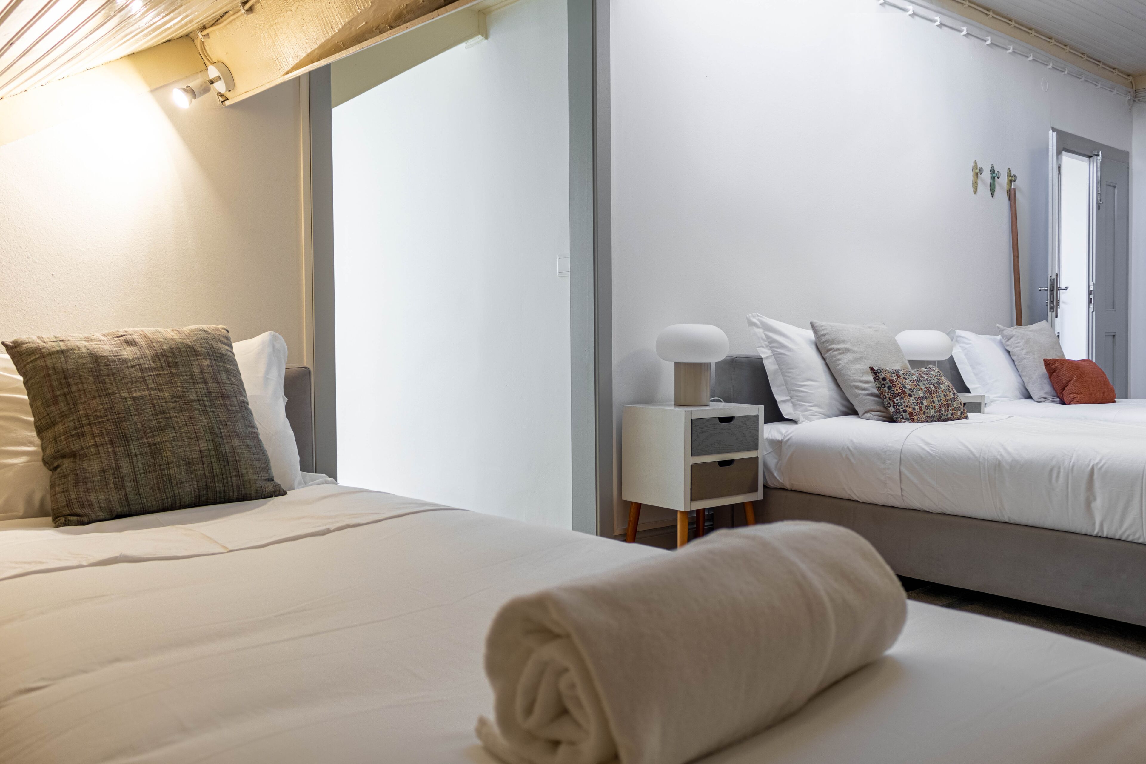 A modern hotel room with two beds, a bedside table, and a nightstand.