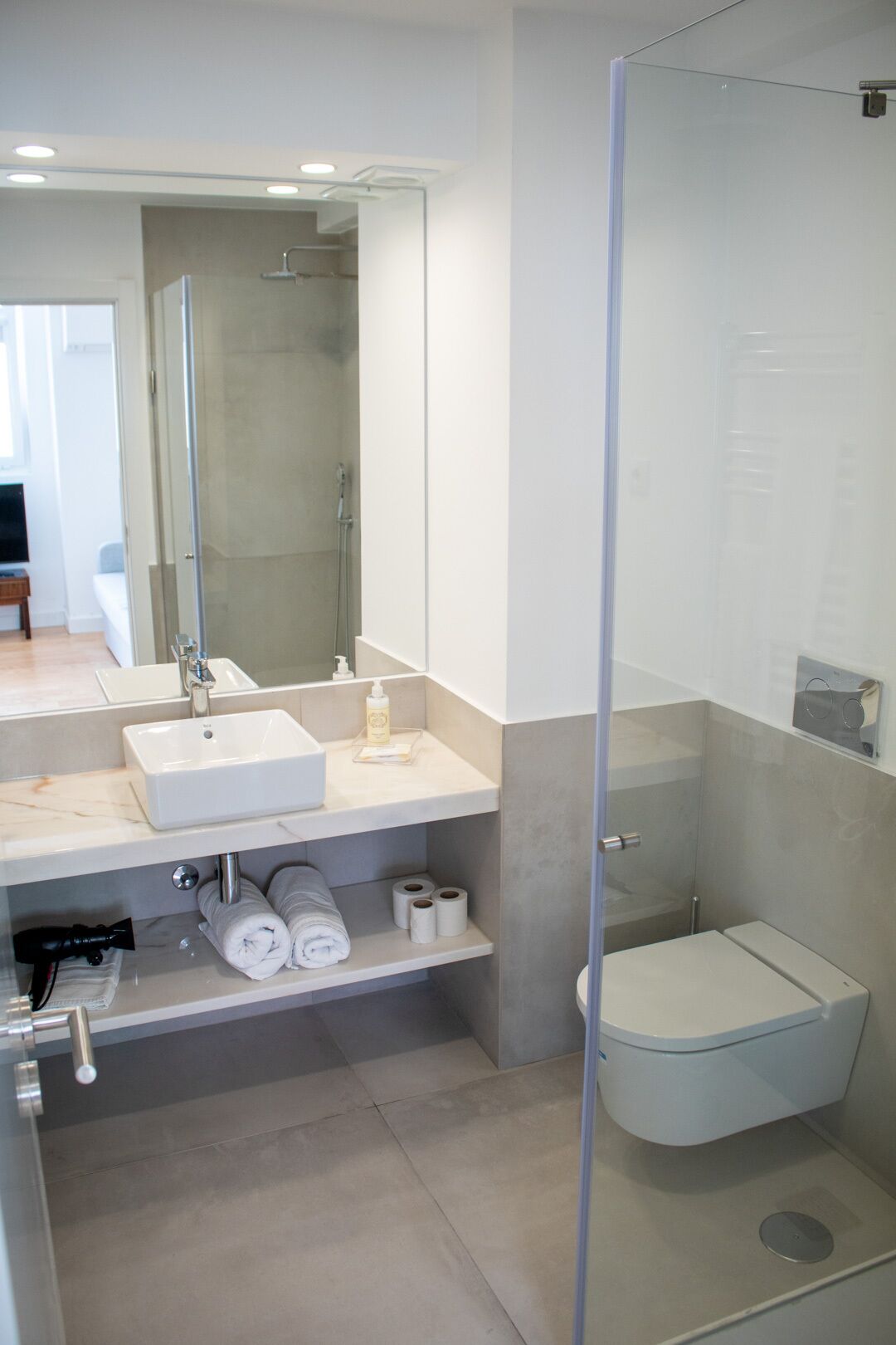 A modern bathroom with a glass-enclosed shower, a white sink, and a toilet.