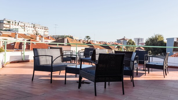 Terraza en la azotea con mobiliario exterior y vistas de edificios circundantes.