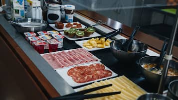 Un bufé con diversos alimentos, incluyendo carnes, quesos y frutas.