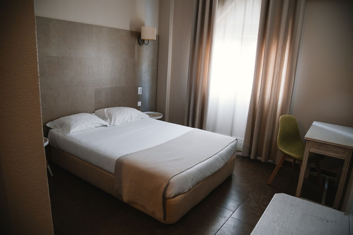 Une chambre d’hôtel avec un grand lit, une table de chevet, une chaise et un bureau.