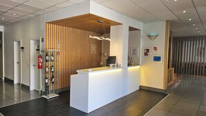 Un área de recepción con un panel de madera, un mostrador de recepción con una computadora y una exhibición de vinos.