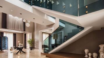A modern interior with a staircase, a dining area, and a large window.