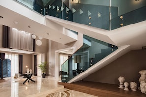 A modern interior with a staircase, a dining area, and a large window.