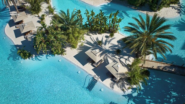An aerial view of a resort with a clear blue pool, palm trees, and sun loungers. - Maxx Royal Belek Golf Resort (Serik)