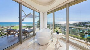 A spacious balcony with a large white bathtub, a lounge chair, and a view of the ocean and resort amenities. - Maxx Royal Belek Golf Resort (Serik)