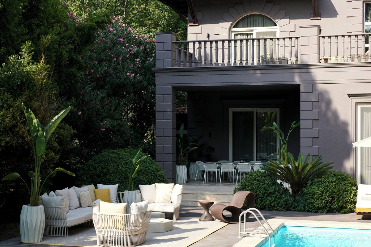 A poolside area with outdoor furniture, a pool, and a building with a balcony.