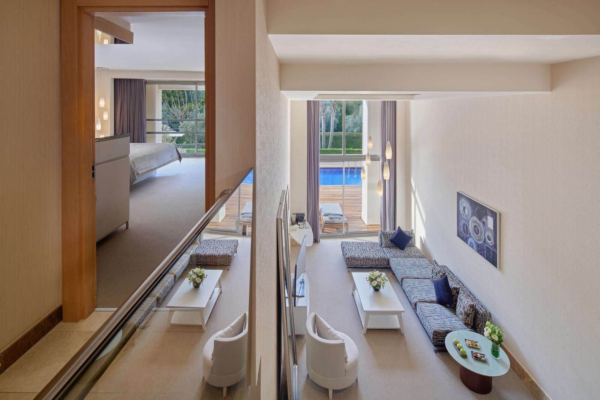 A modern hotel room with a balcony, a sofa set, and a dining area.