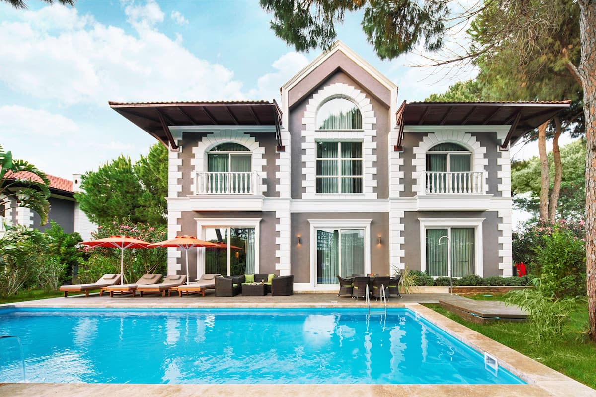 A two-story house with a swimming pool, outdoor seating, and a well-maintained garden.
