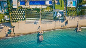 An aerial view of a beach resort with multiple pools, sun loungers, and a pier. - Maxx Royal Belek Golf Resort (Serik)