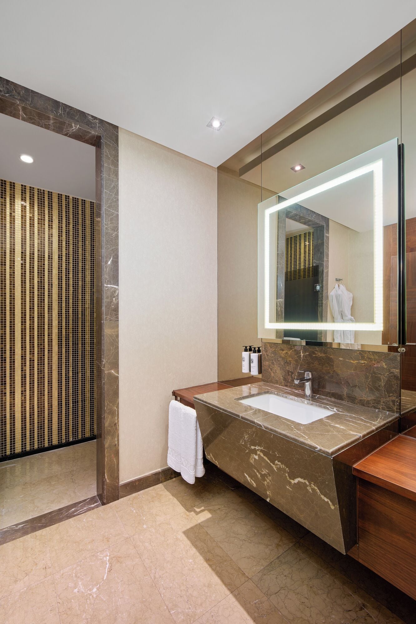 Une salle de bain moderne avec un lavabo en marbre, un grand miroir et un porte-serviettes.
