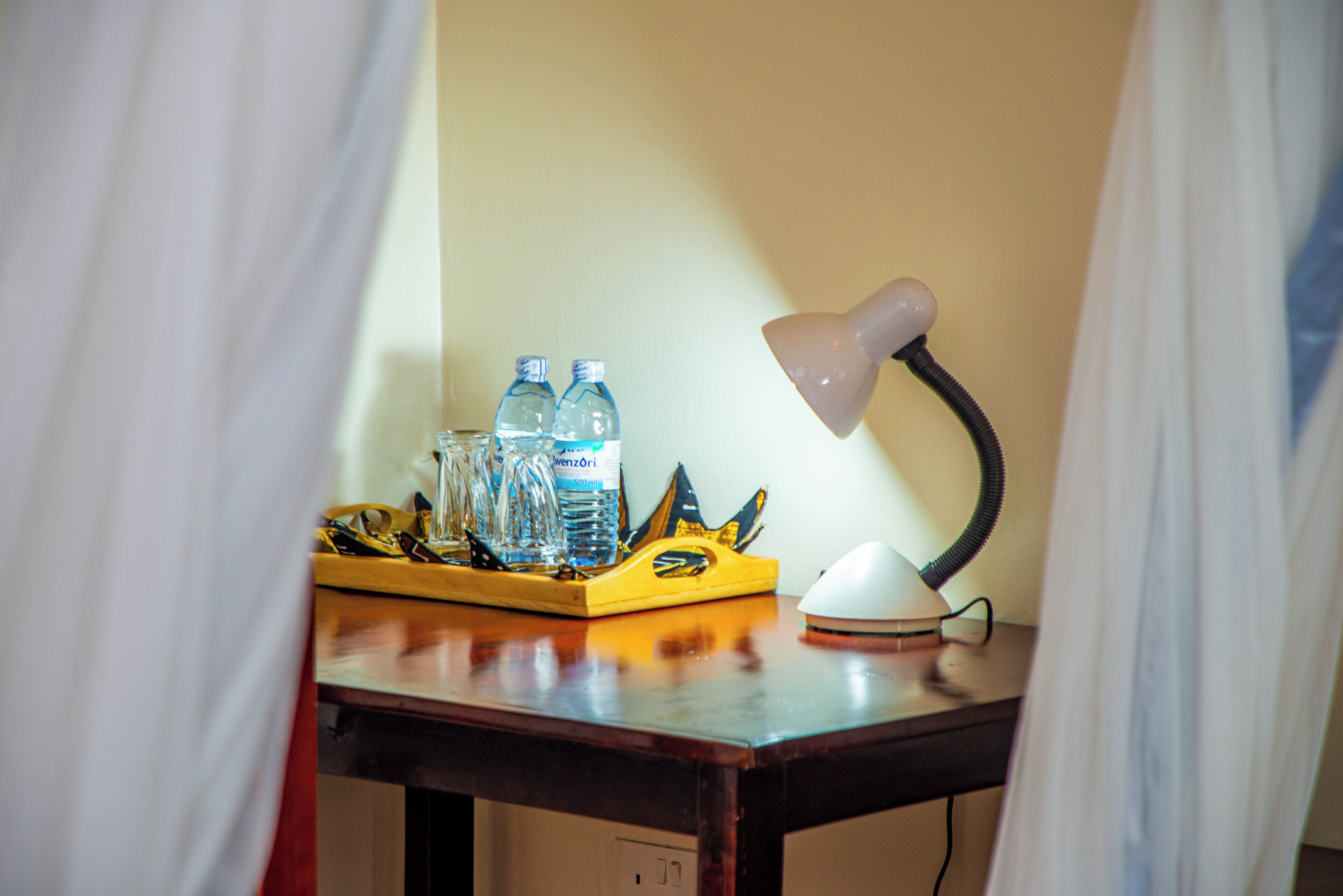 Ein Schreibtisch mit Lampe, Wasserflaschen und einer gelben Ablagefläche.