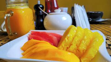 A breakfast plate with sliced fruits and a glass of orange juice.