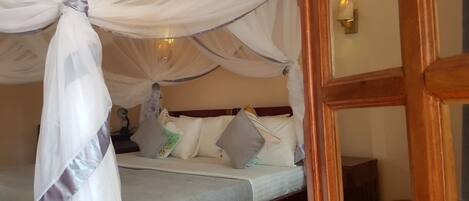 A bedroom with a four-poster bed, white bedding, and a canopy.