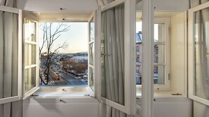 A room with large windows, a view of a snowy street and buildings, and a visible door. - Hoffmeister Depandance (Prague)