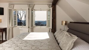 A bedroom with a large bed, a view through an open window, and a bedside table. - Hoffmeister Depandance (Prague)