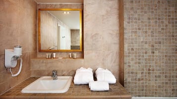 A bathroom with a large mirror, a sink, and a bathtub.