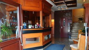Un hall de hotel con una recepción, una escalera y una zona de estar.