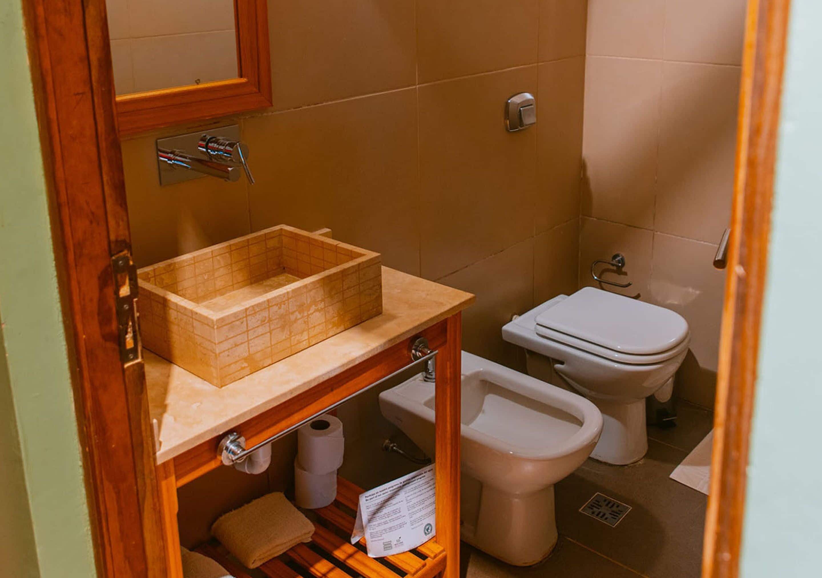 A small bathroom with a wooden vanity, a toilet, and a bidet.