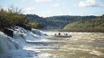 A river with a waterfall and a boat with people.