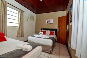 Habitación de hotel con dos camas, techo de madera, un cuadro enmarcado en la pared y una puerta con panel de madera.