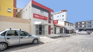 A hotel with a red and white facade, a visible entrance, and a parking area with cars. - Hotel Diamante Negro - Salvador (Salvador)