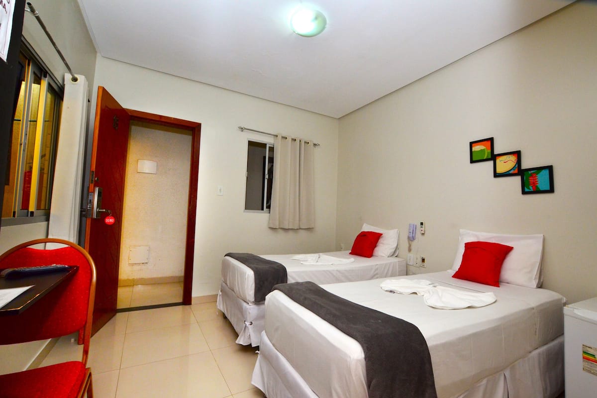 A hotel room with two beds, a desk, and a chair.