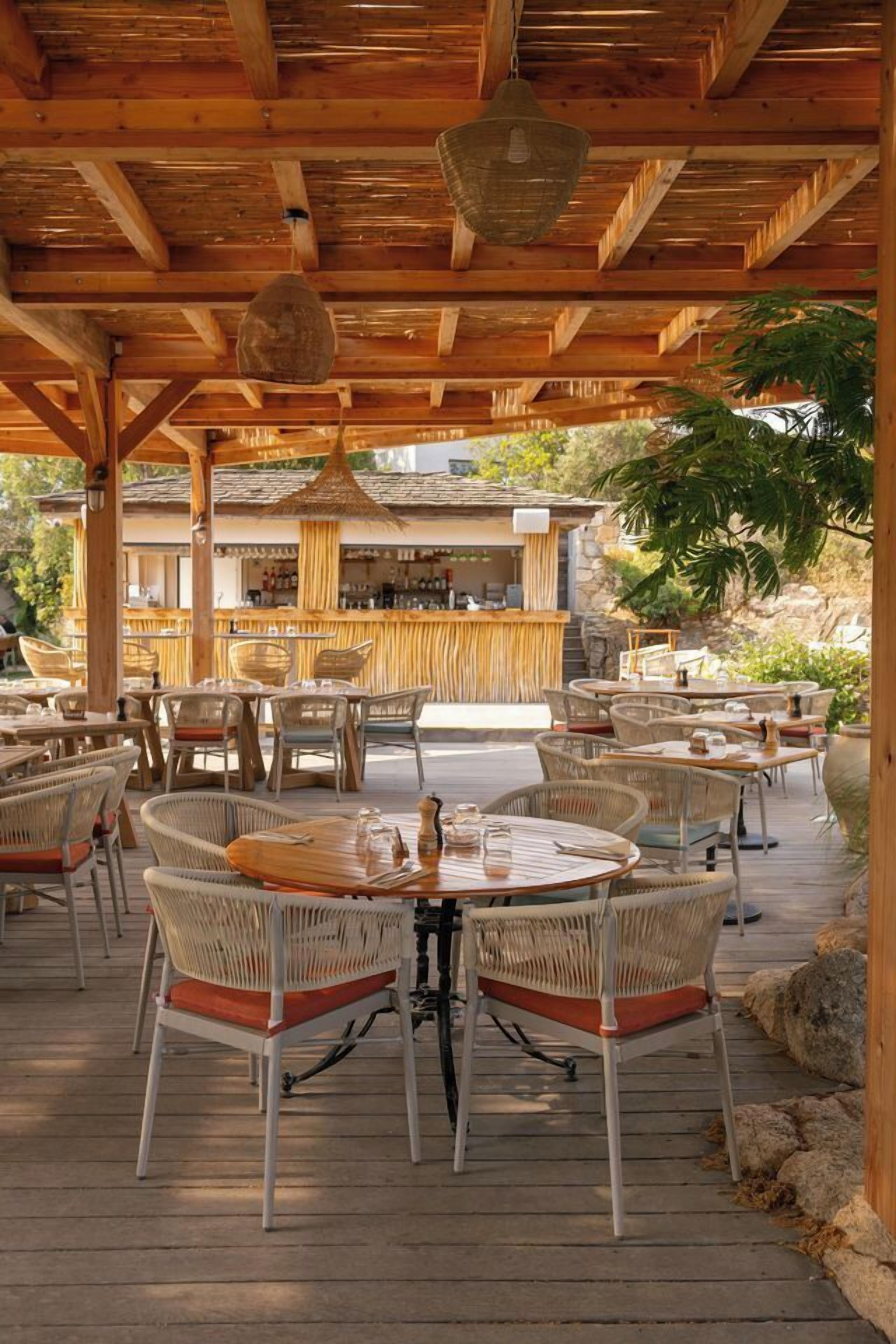 An outdoor patio with wicker furniture and a bar area in the background.