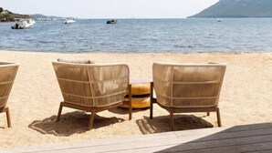 A beachside seating area with wicker chairs and a wooden deck overlooking the sea. - Hotel Marina Corsica (Porto-Vecchio)