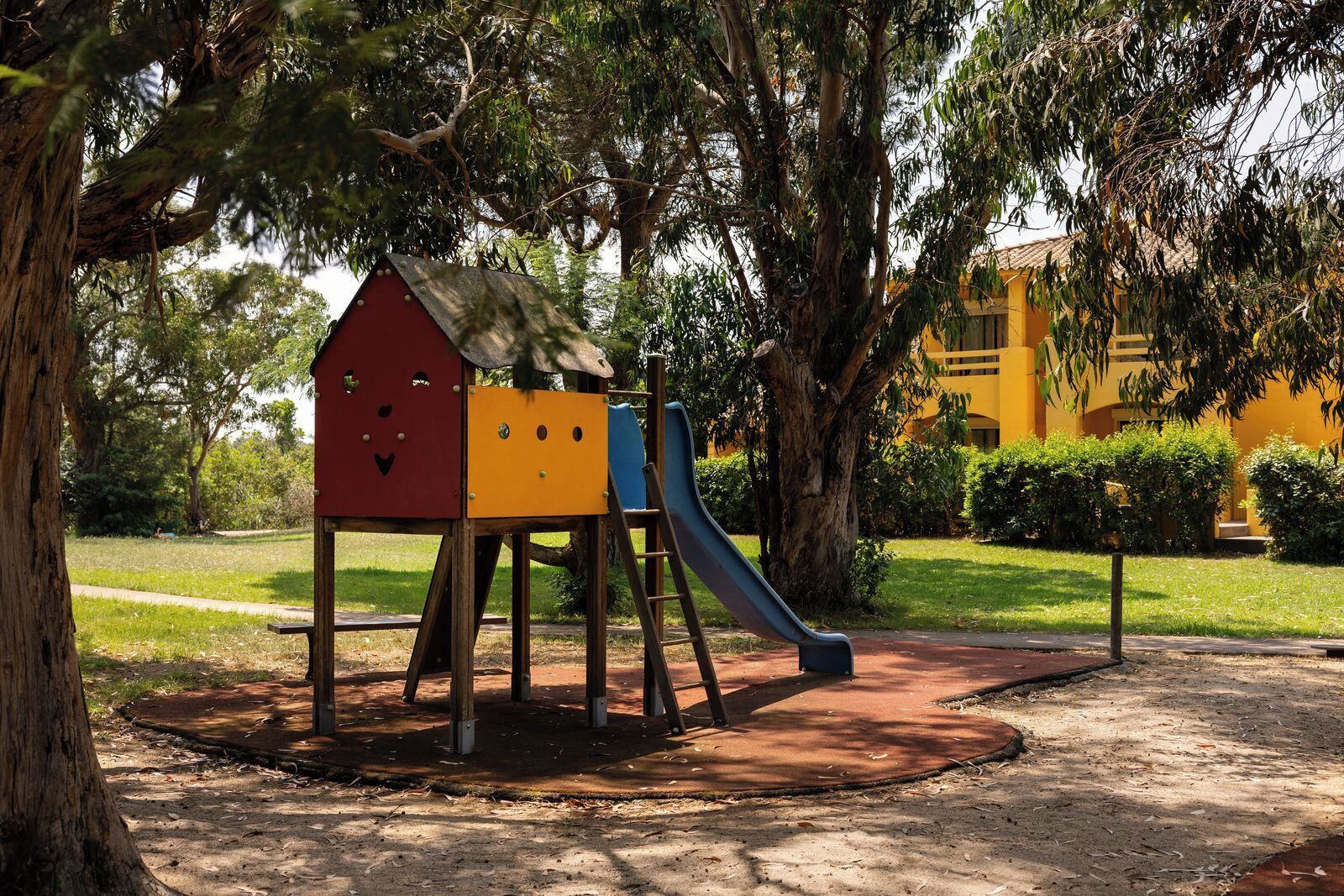 A playground with a slide and a house-shaped climbing structure.