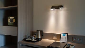 Una habitación de hotel con cafetera, balanza, bandeja con vasos y control remoto.