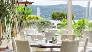 A restaurant with round tables and white chairs, overlooking a lake and hills. - Hotel Marina Corsica (Porto-Vecchio)