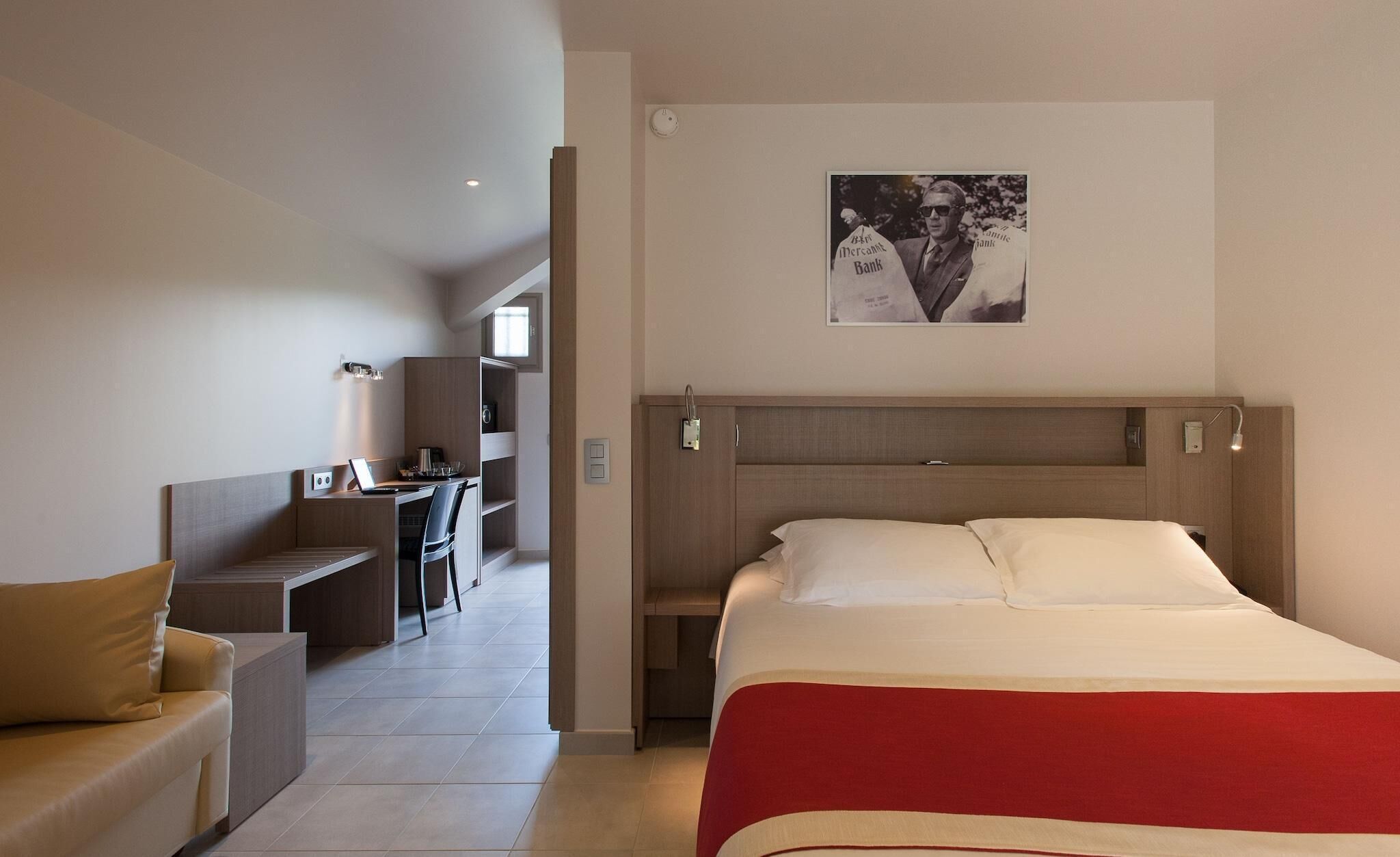 A hotel room with a bed, a desk, a chair, and a couch.
