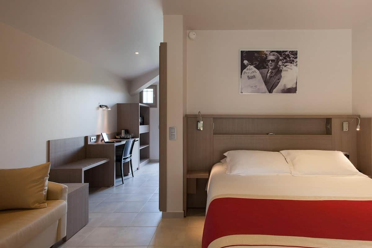 Una habitación de hotel con una cama, un escritorio, una silla y un sofá.