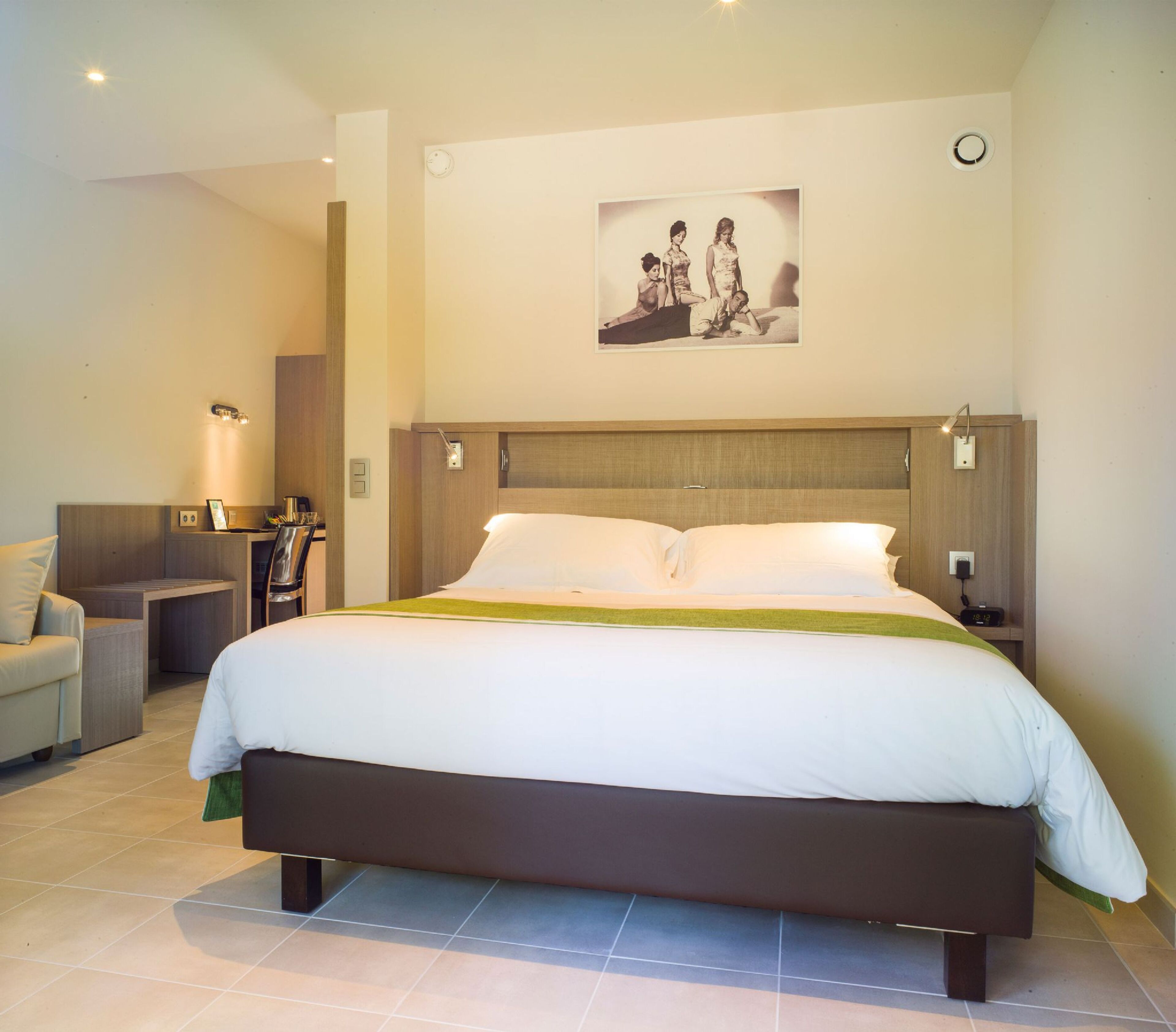 A hotel bedroom with a large bed, bedside tables, a desk, and a chair.