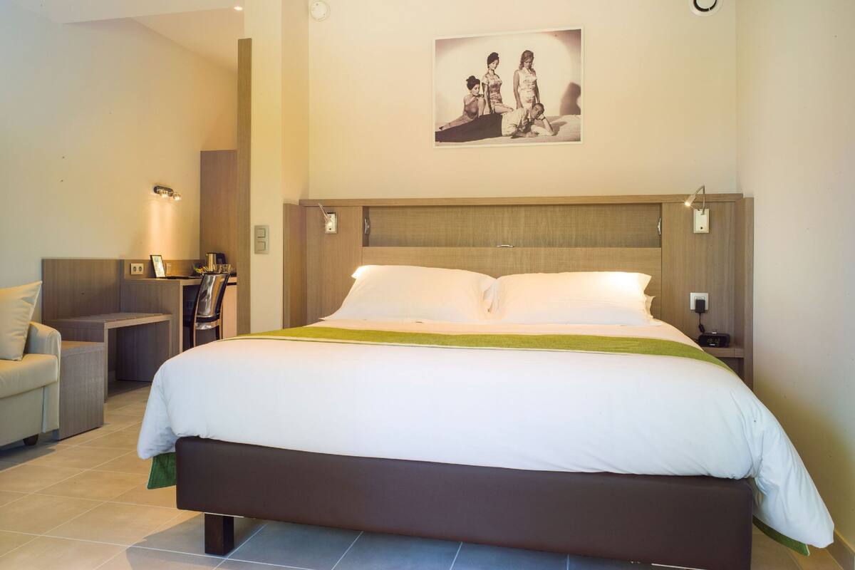 Un dormitorio de hotel con una cama grande, mesitas de noche, un escritorio y una silla.