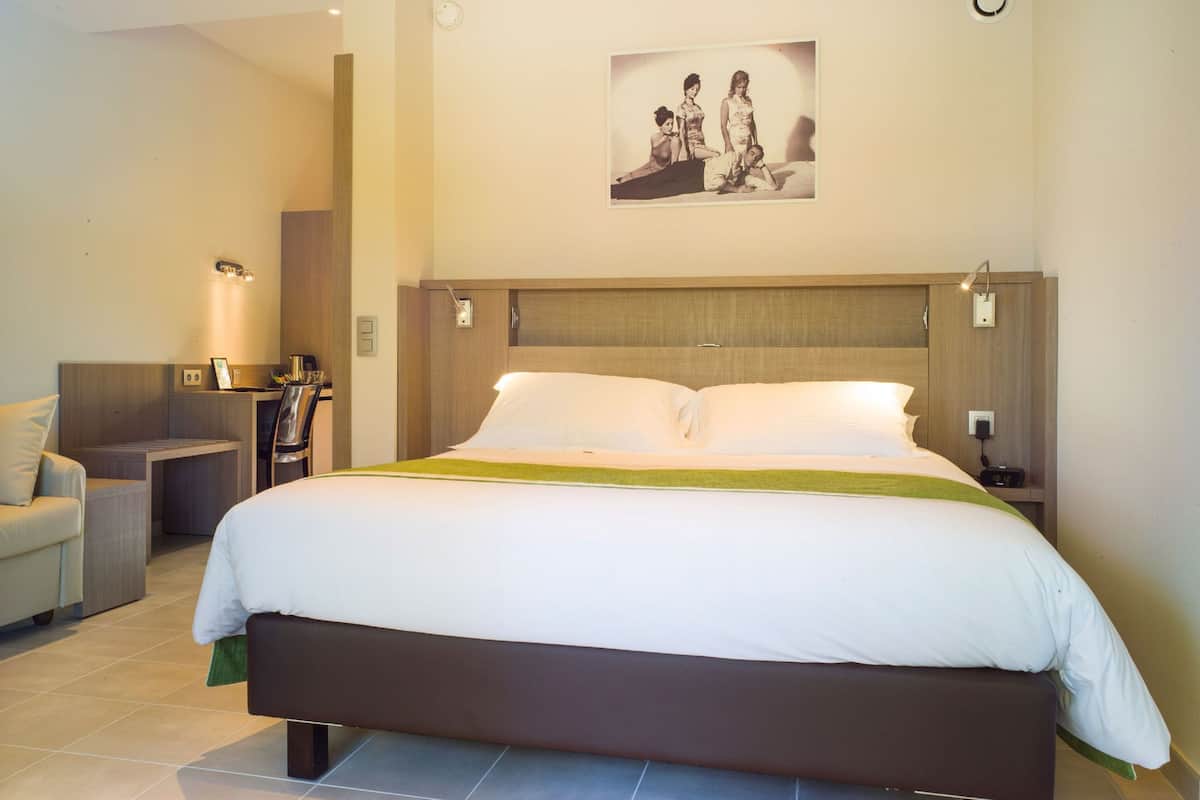 A hotel bedroom with a large bed, bedside tables, a desk, and a chair.