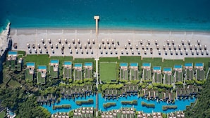 Vista aérea de un complejo turístico con varias piscinas, una playa y una estructura alta en el centro.
