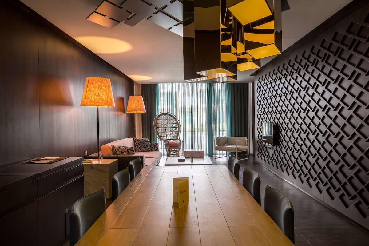 A modern conference room with a long table, chairs, a sofa, and a patterned wall.