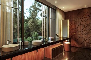 A modern bathroom with a large window, a round sink, and a wooden vanity.